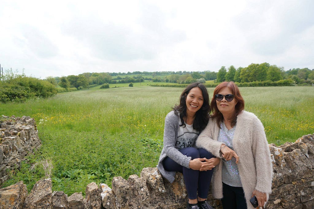 Photo of Eggya sitting next to her mother in the English countryside.