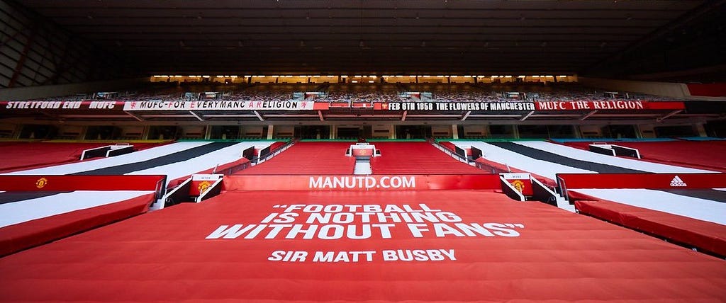 Old Trafford banner reading “Football is nothing without fans” — Sir Matt Busby
