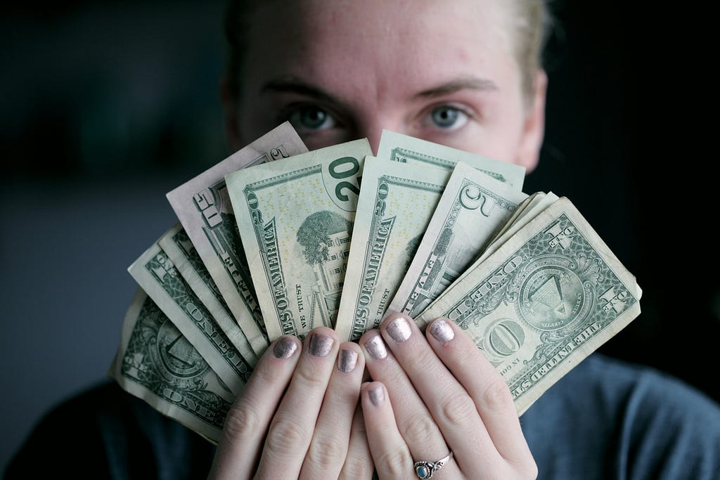 A person holding cash in front of their face