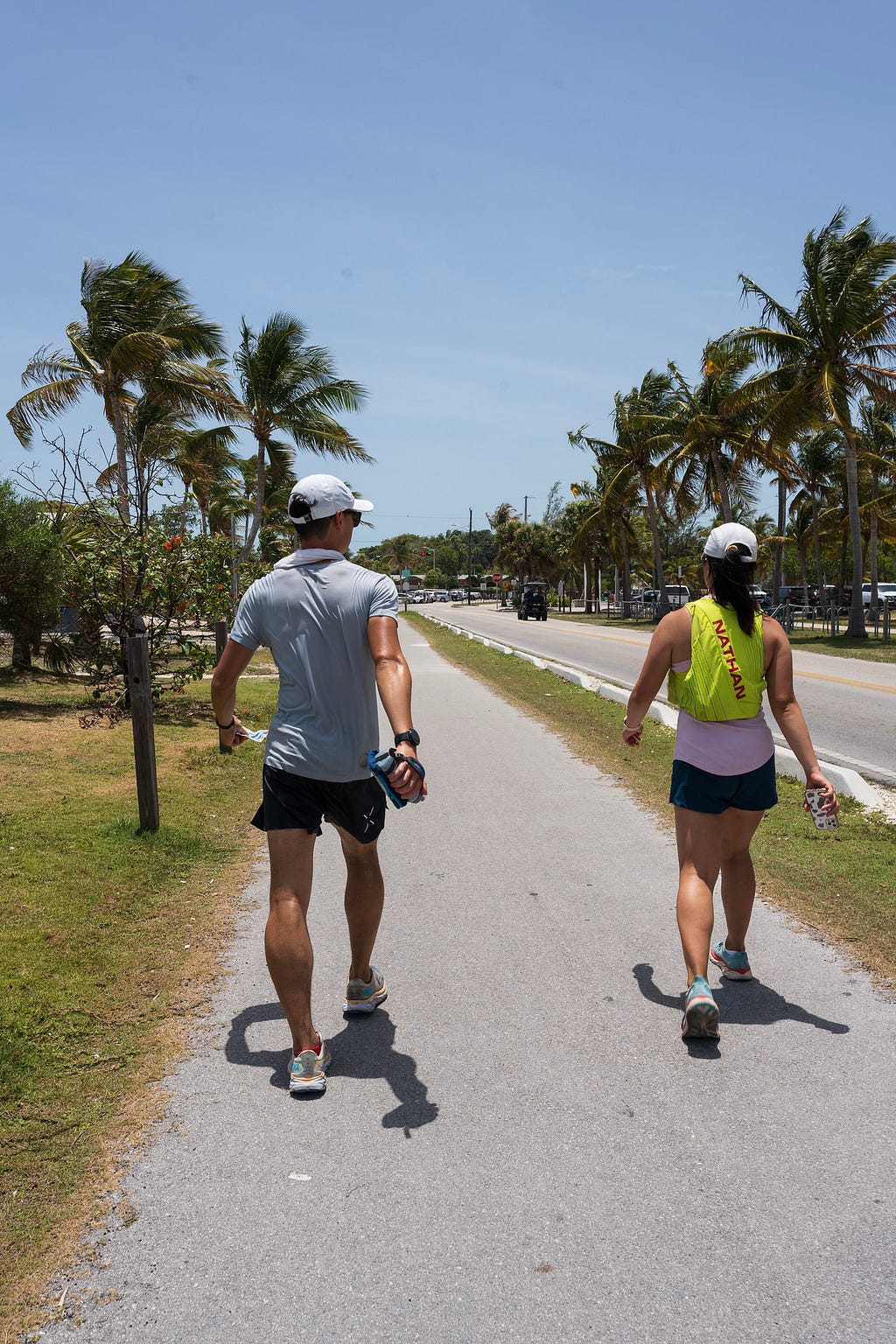 Photo of me walking on a sidewalk next to the road with palm trees on the sides. In the florida keys during the keys 100 race