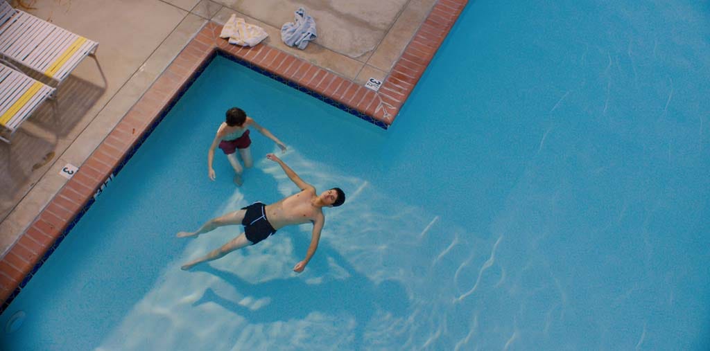 Ari and Dante in the pool, with Ari floating as Dante instructs him on what to do. The two are the only people in the shot.