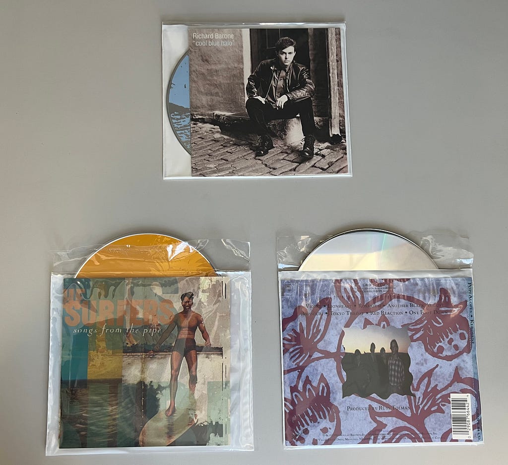 Three CDs in poly sleeves, different views.