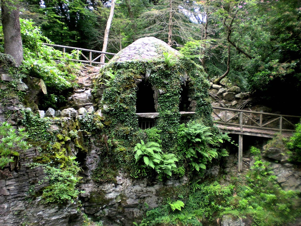 Tollymore Forest; man-made brickwork oozing with green plant life and foliage. The central structure looks like a face.
