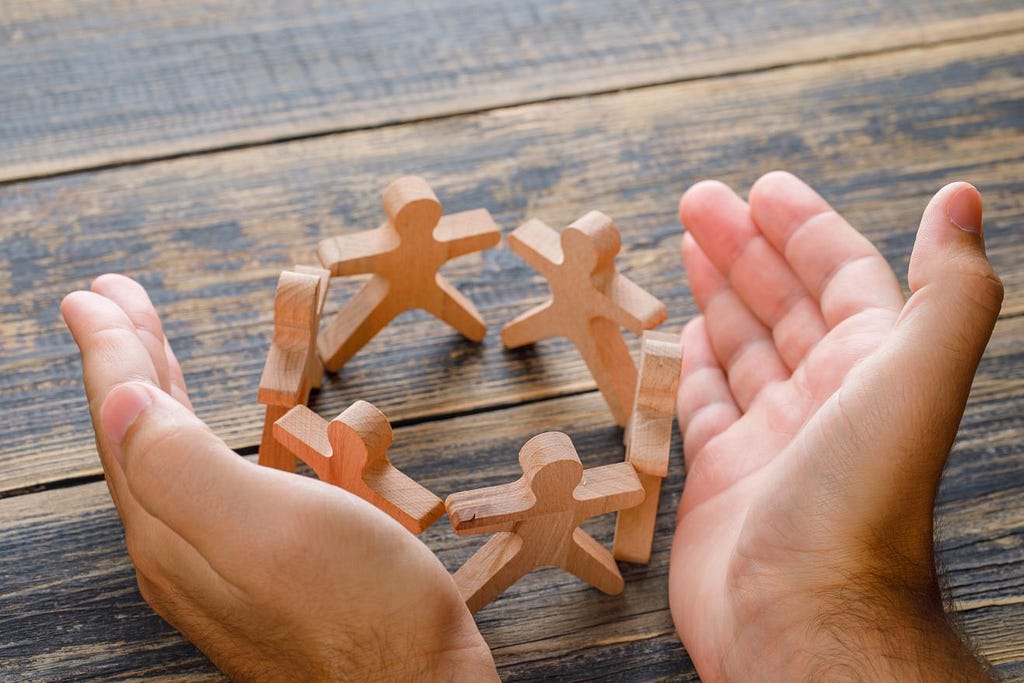 a photo of a hand protecting wooden figures