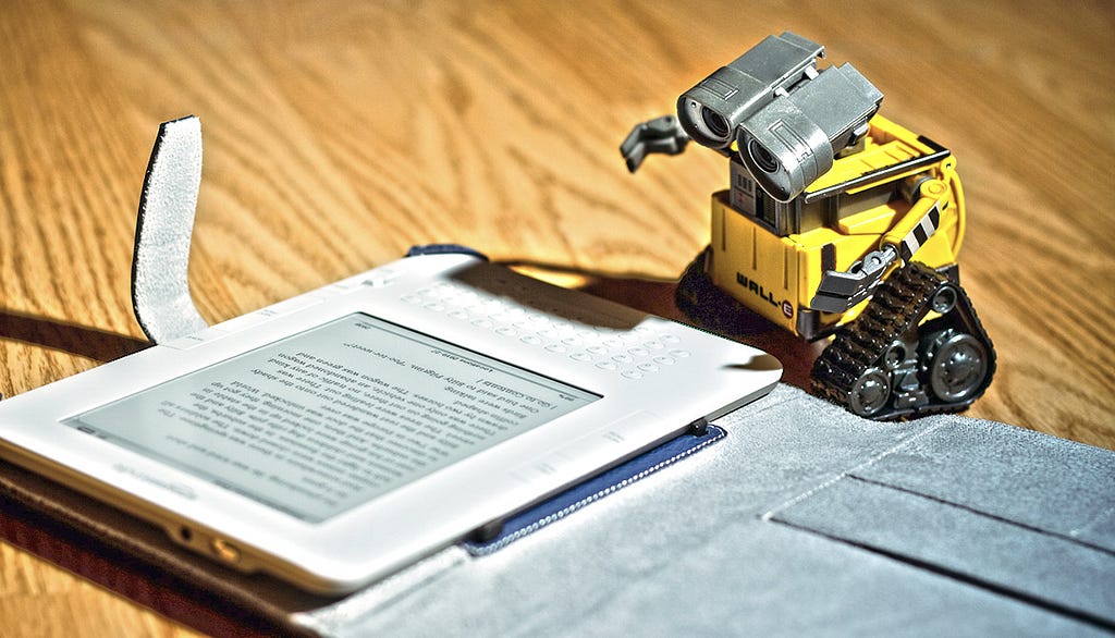 toy robot looking like it is reading from a Kindle device