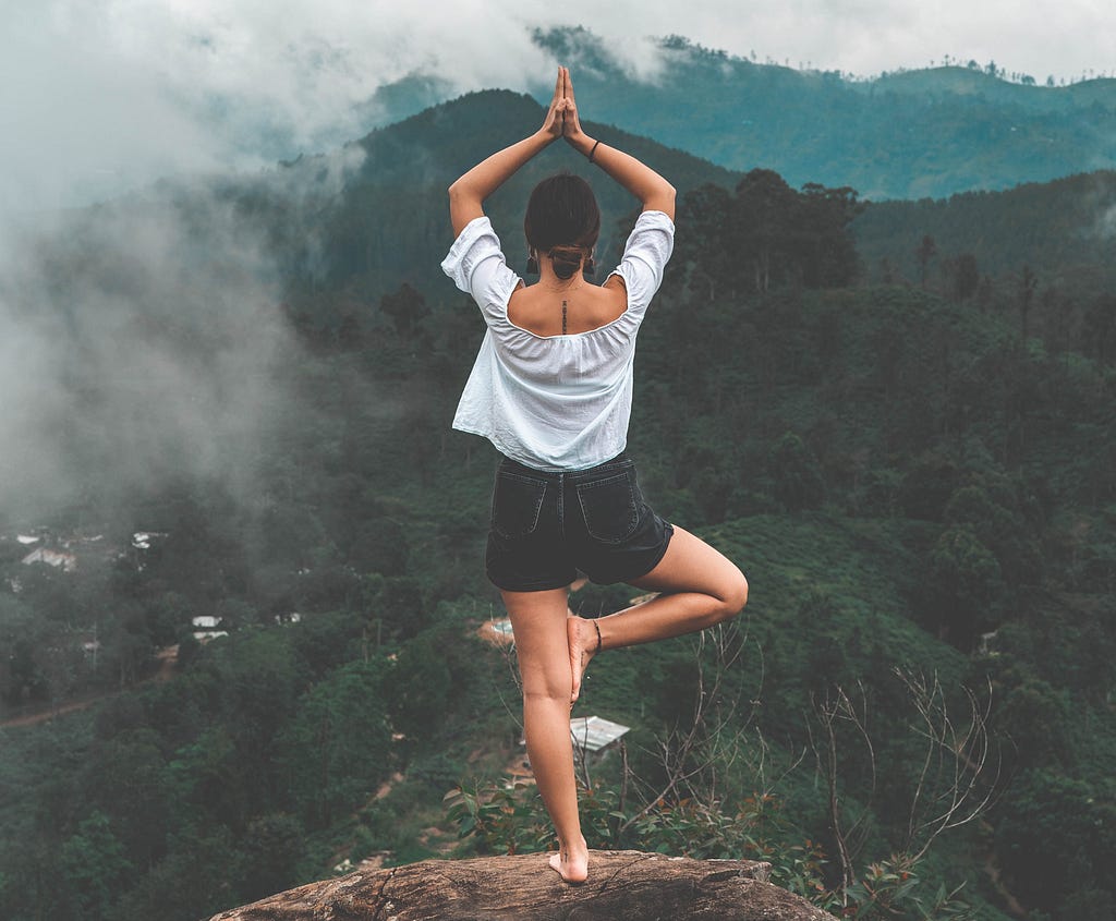 A girl meditating and doing yoga at the top of mountain. Find balance in life by Abhay Gautam