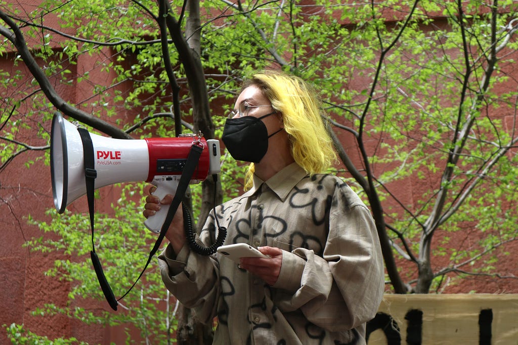 Tracy Rosenthal speaks into a megaphone to tell the crowd about NYU Divest