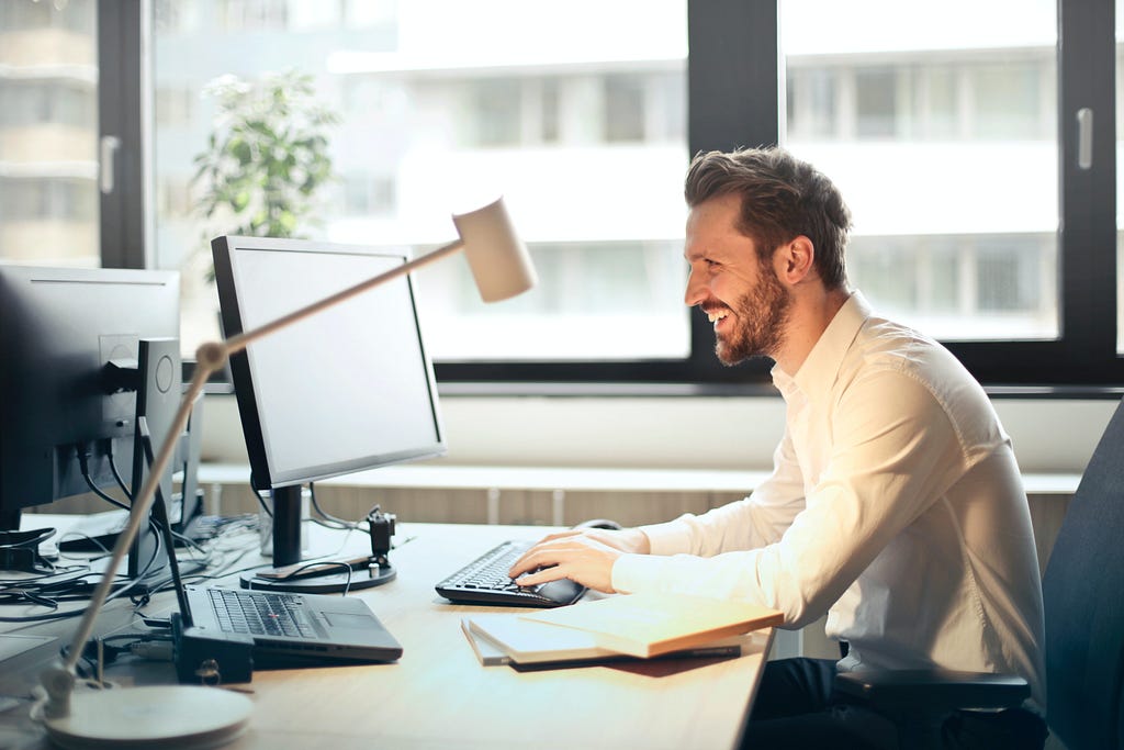 A Freelancer smiling while staring at his Desktop
