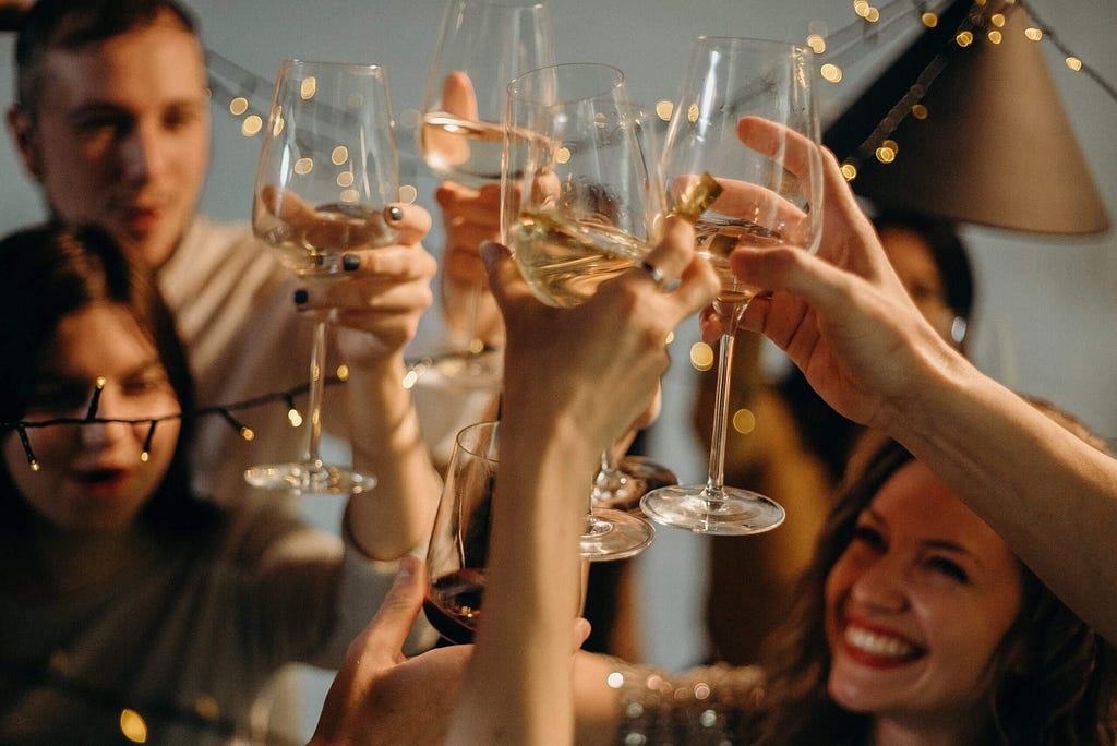 People holding glasses of wine and celebrating their success.