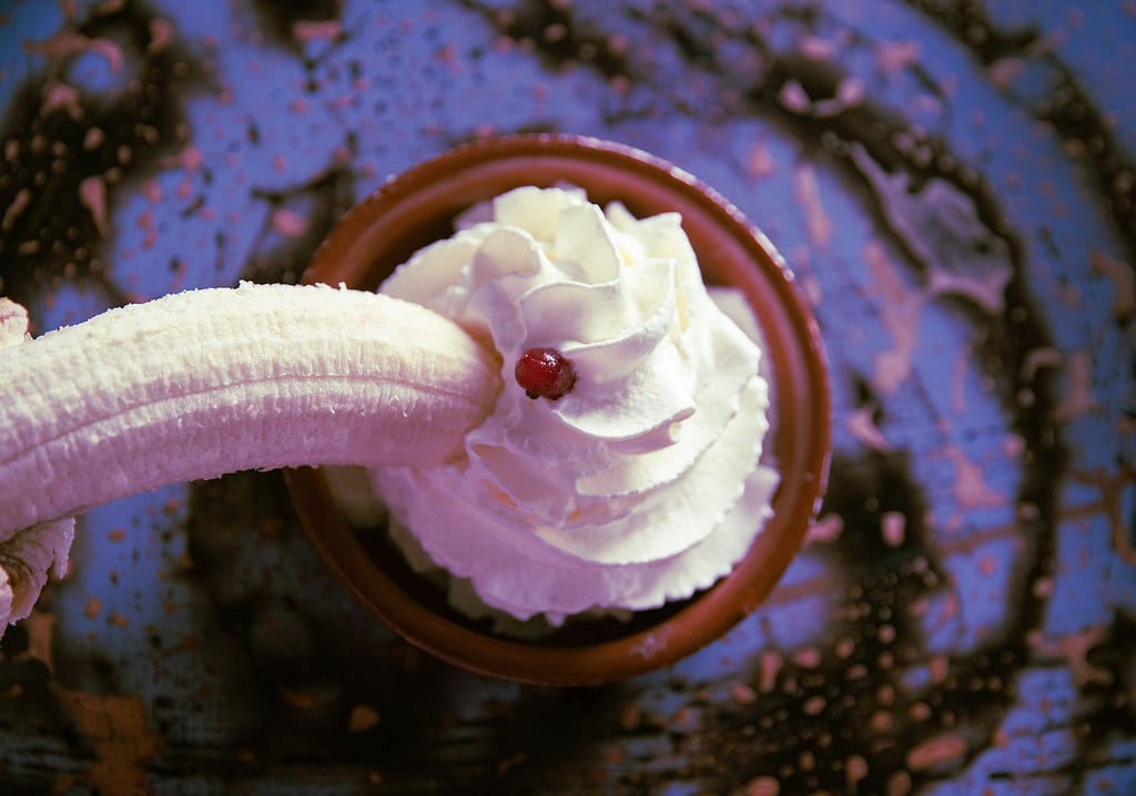 A banana being dipped into a dessert