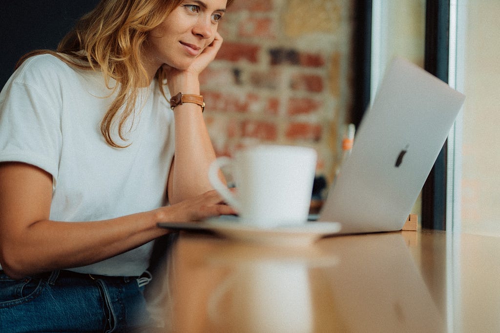 A woman sits in a cafe looking at her laptop