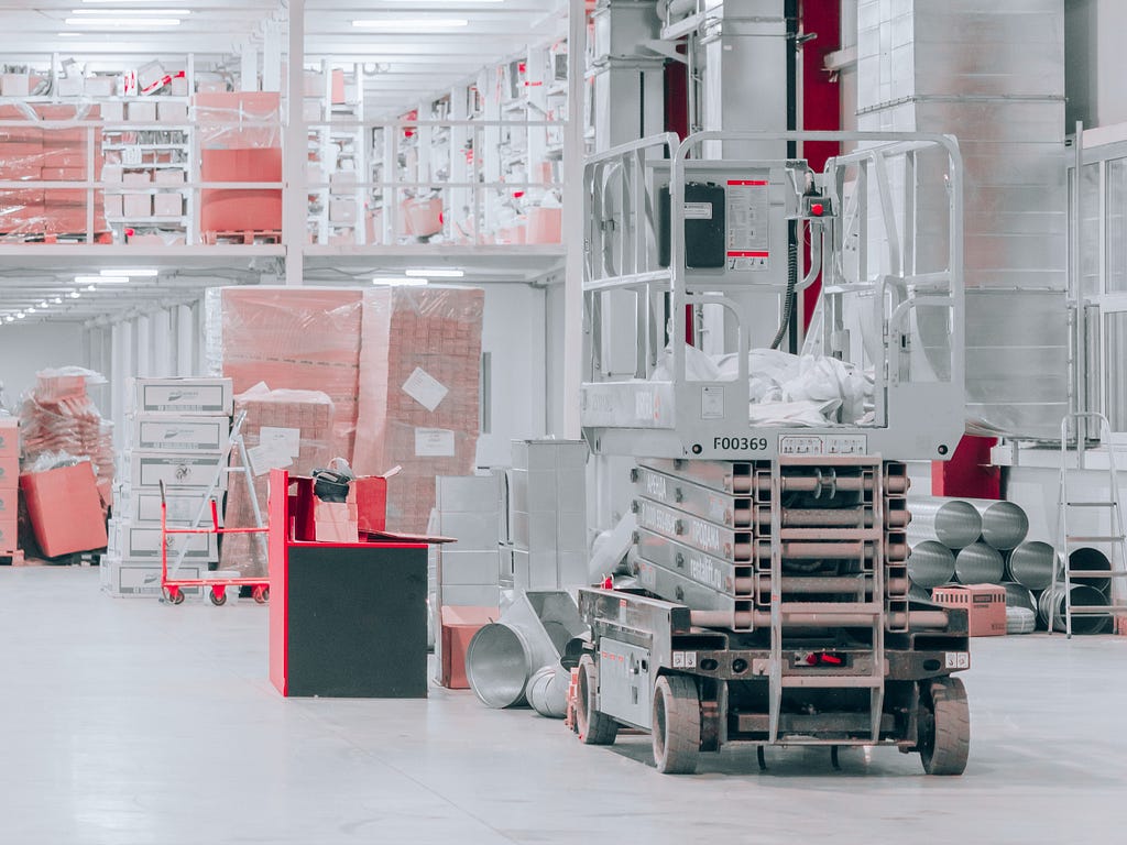 a white warehouse with orange boxes and a motorized cart