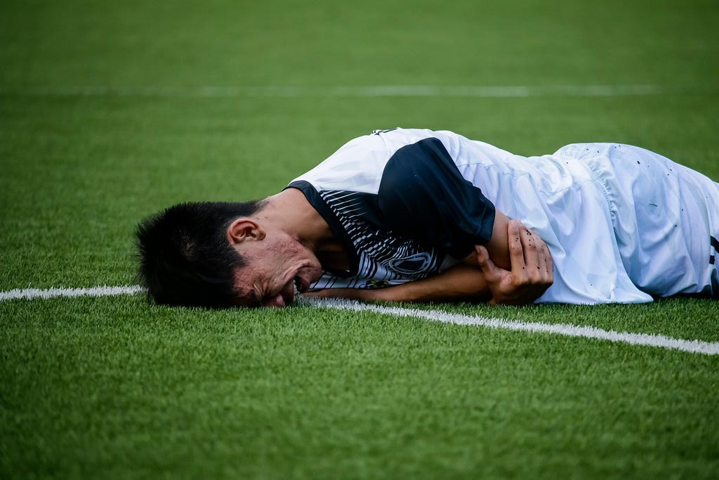 A picture of a Soccer player laying face down injured and exhausted