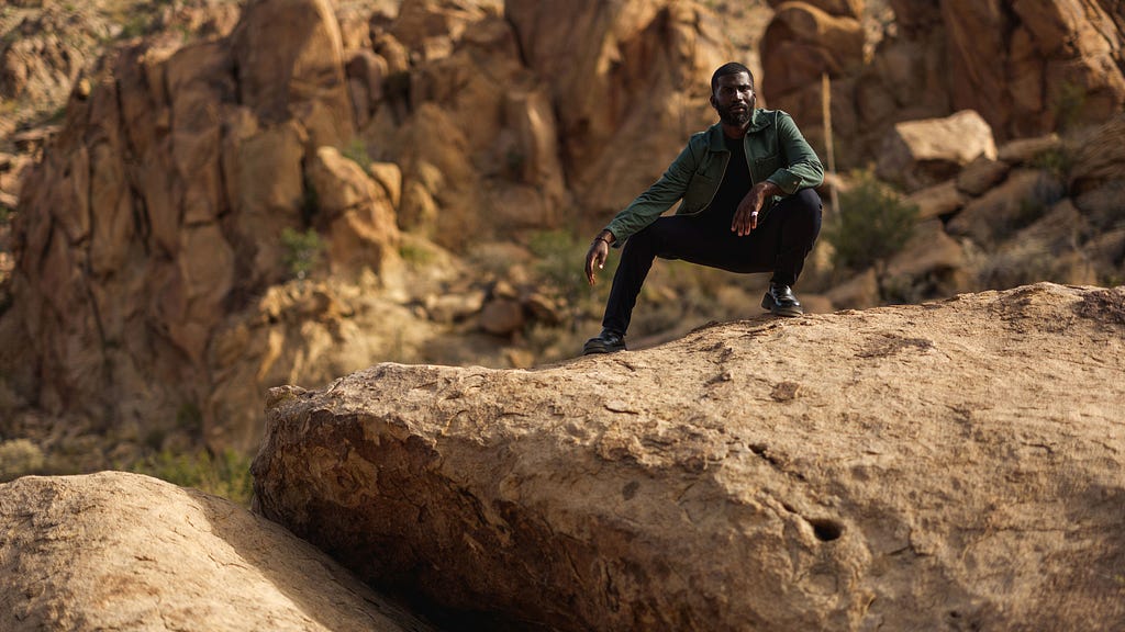 Young man crouching on rock in desert