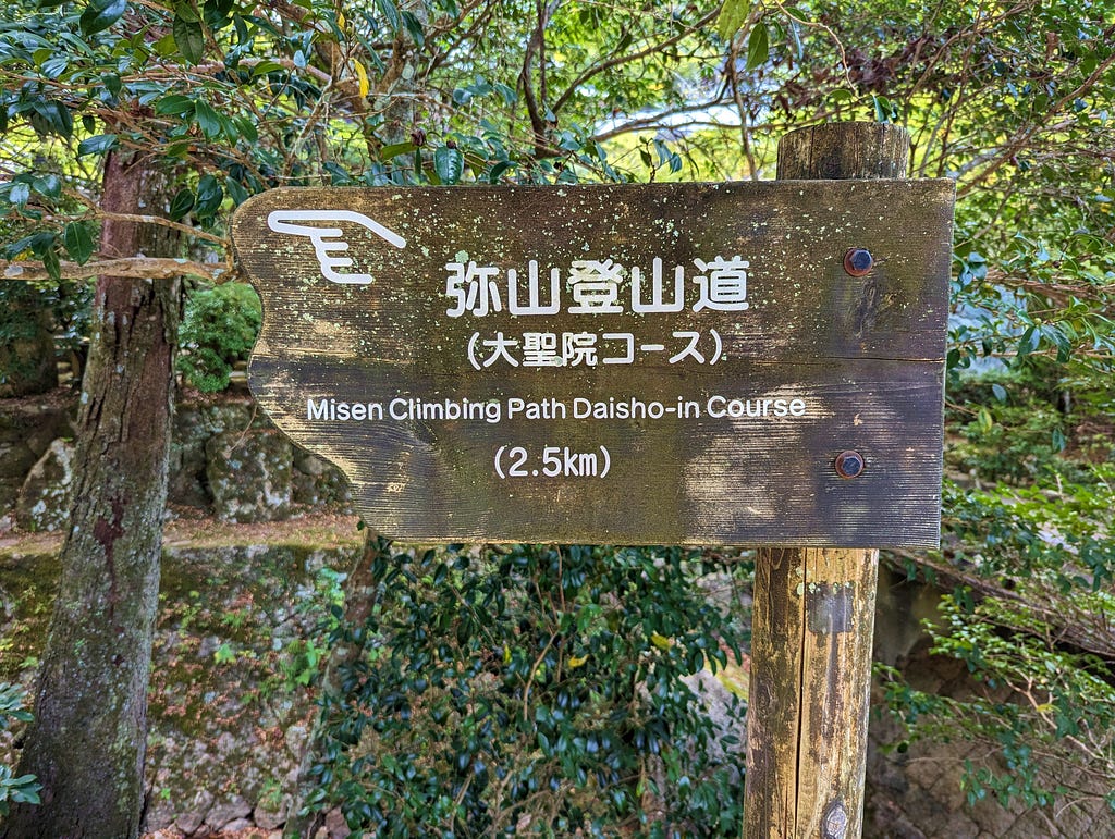 Wooden sign with hand pointing the way to the Misen Climbing Path