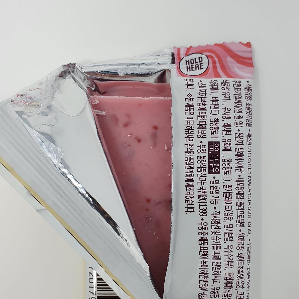 A partially opened bar of Hershey’s Strawberries ’n’ Creme revealing the back of the bar.