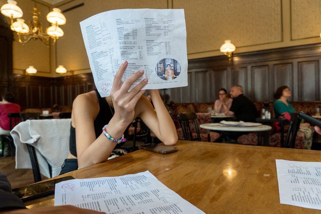 A girl holding up a menu covering her face