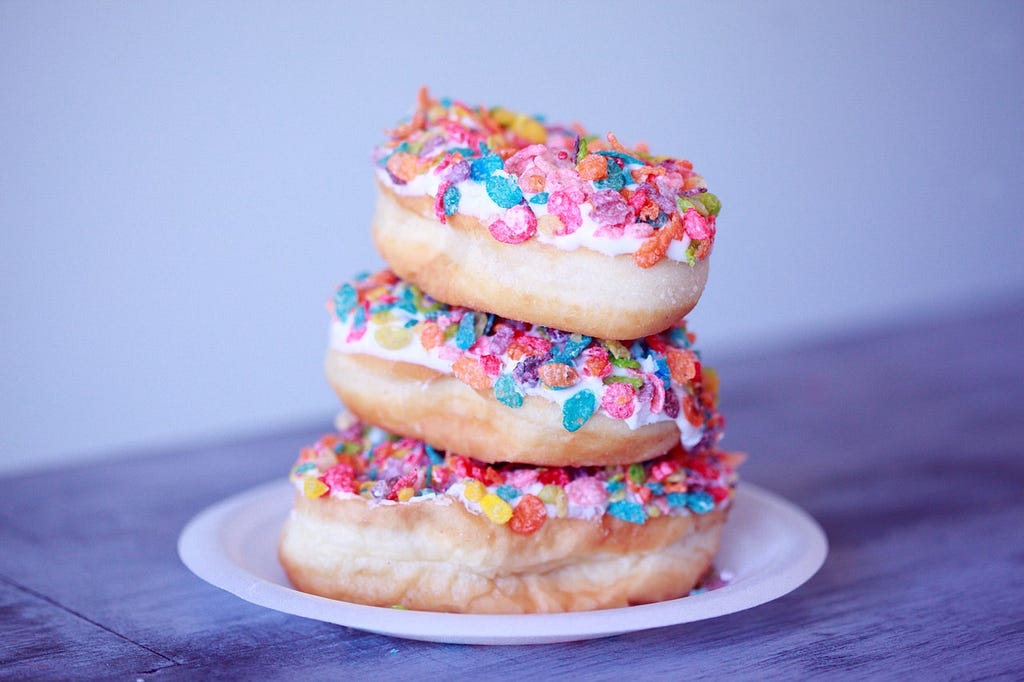 Three donuts with sprinkles stacked on top of each other.