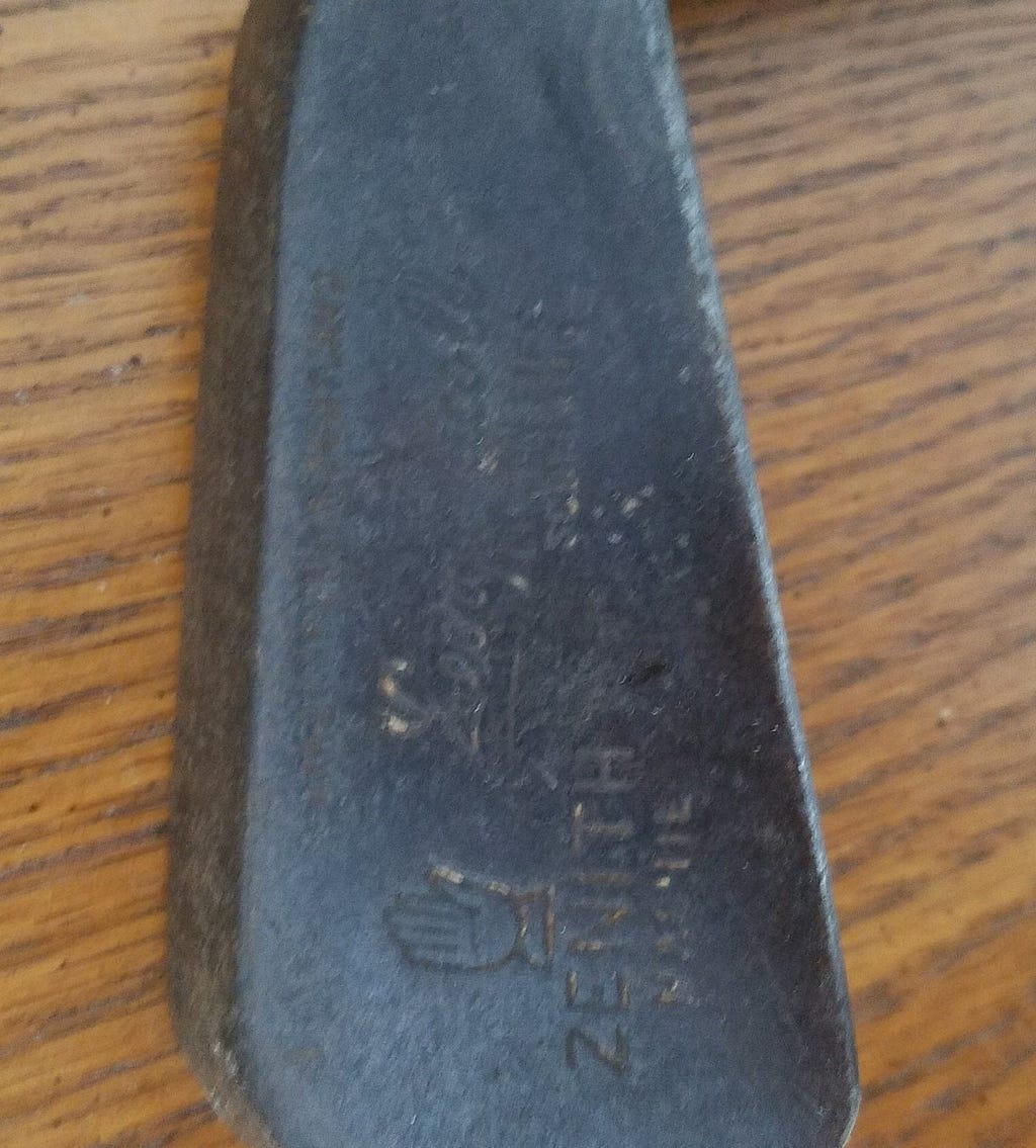 A picture of a forged iron golf club head with an inscription. Photo by author.