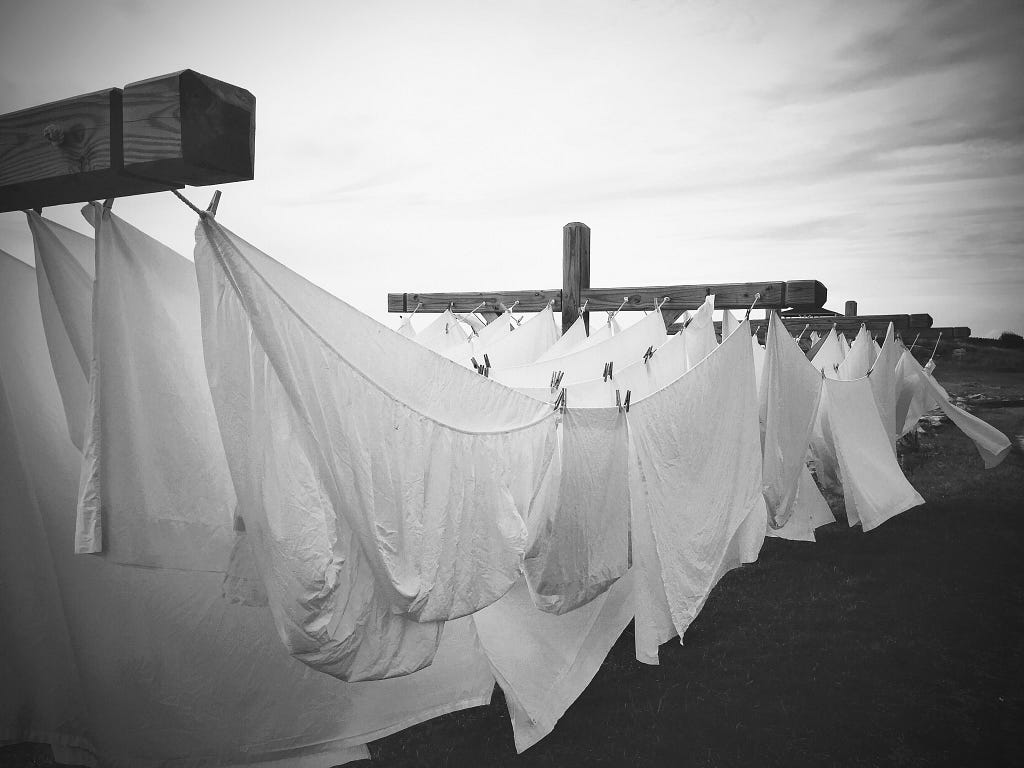 black and white photo of bed sheets drying on a clothes line outside