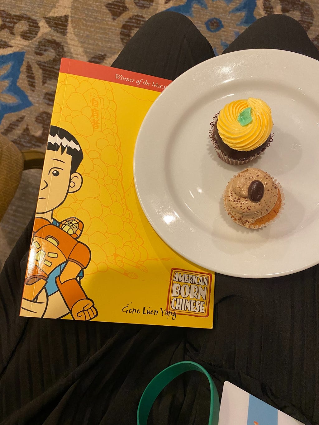 plate of two small cupcakes on top of a copy of graphic novel American Born Chinese by Gene Luen Yang