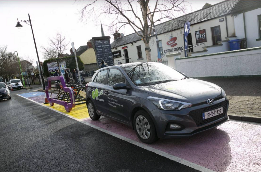 Parking spots of different colors with a car and bikes parked