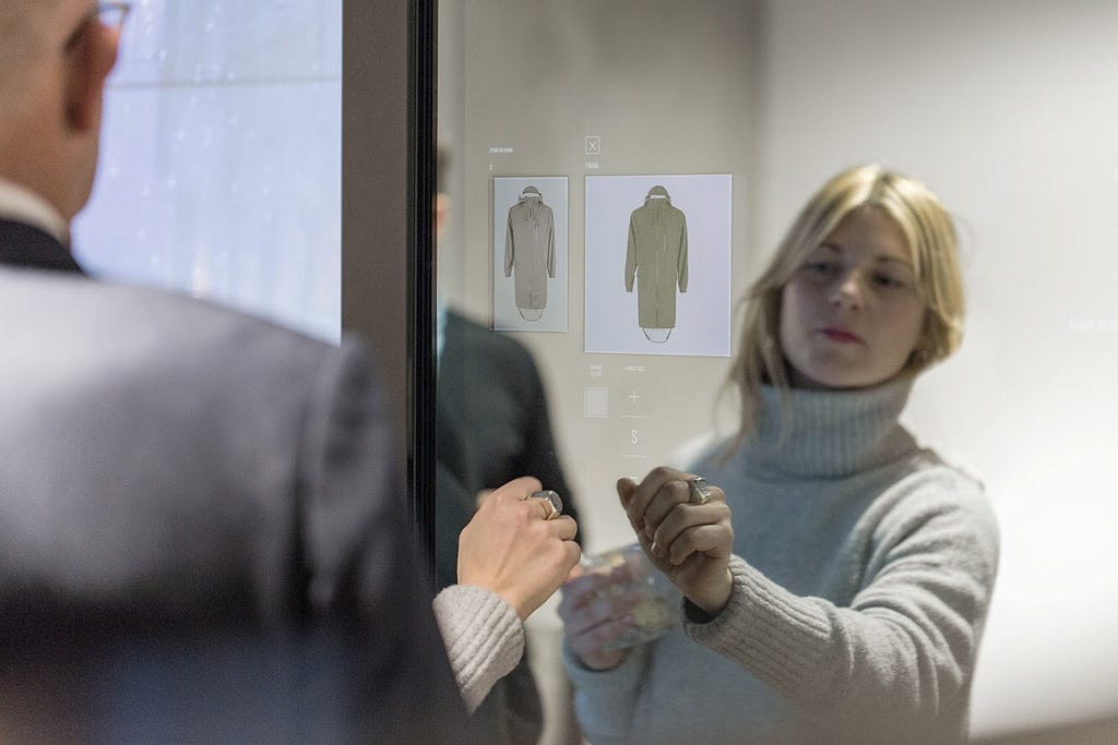 A woman touches a mirror on which coats light up