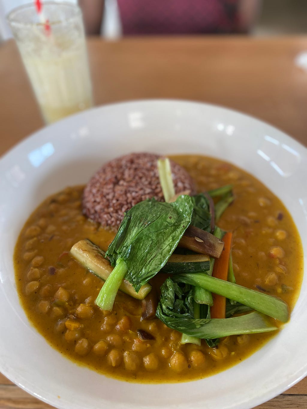Chickpea curry with brown rice and steamed veggies set in a white bowl, Tatale Vegan Restaurant