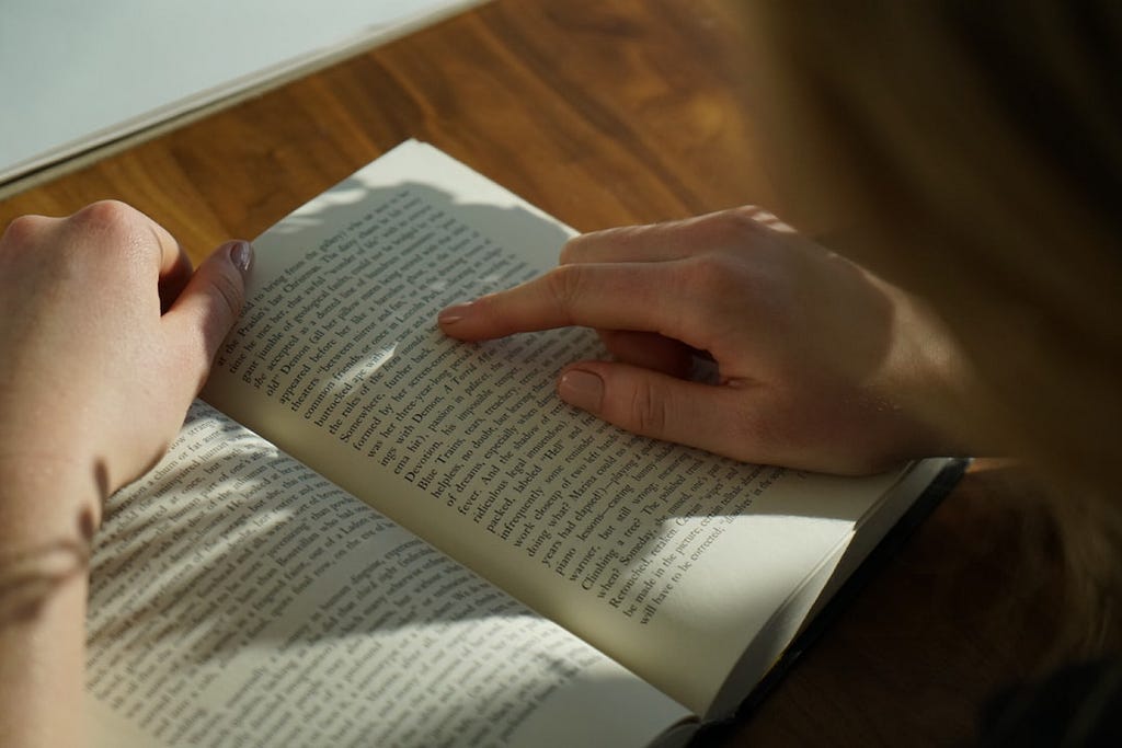 An open book with a person’t finger on it helping with the reading faster