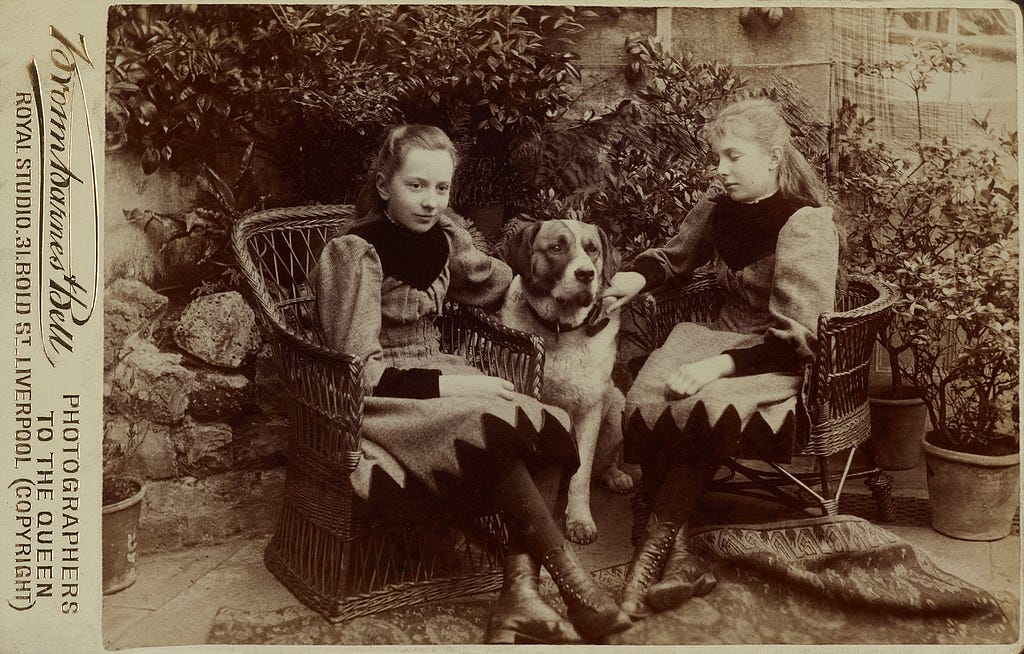 Photograph of Margaret Pilkington and her sister Dorothy as children sat in a garden with with their dog