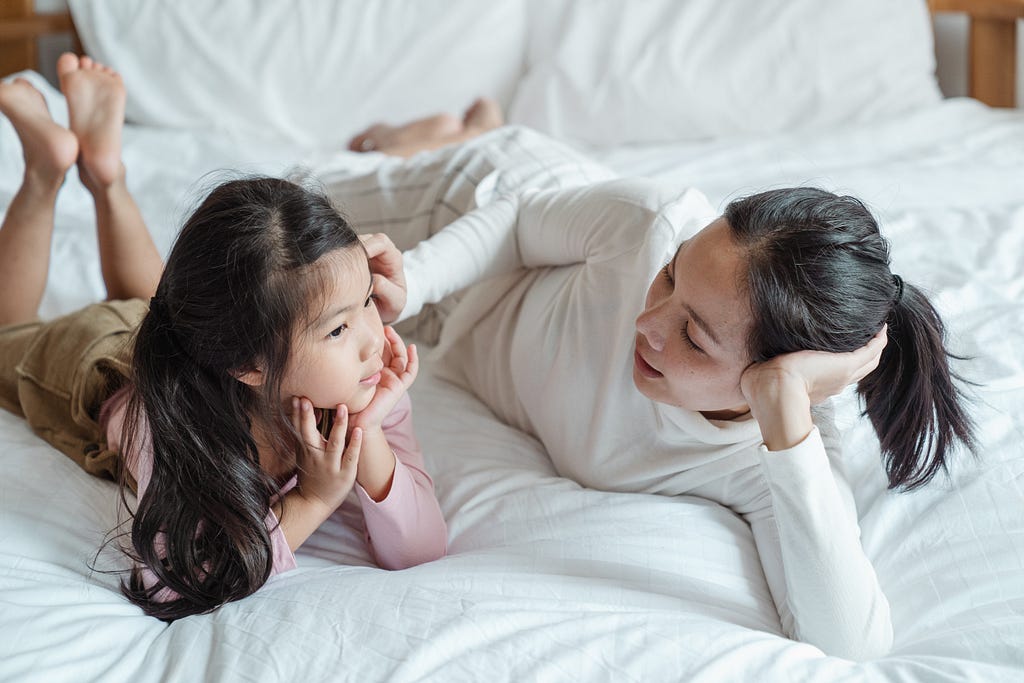 Mother lovingly talking to her daughter on a bed.