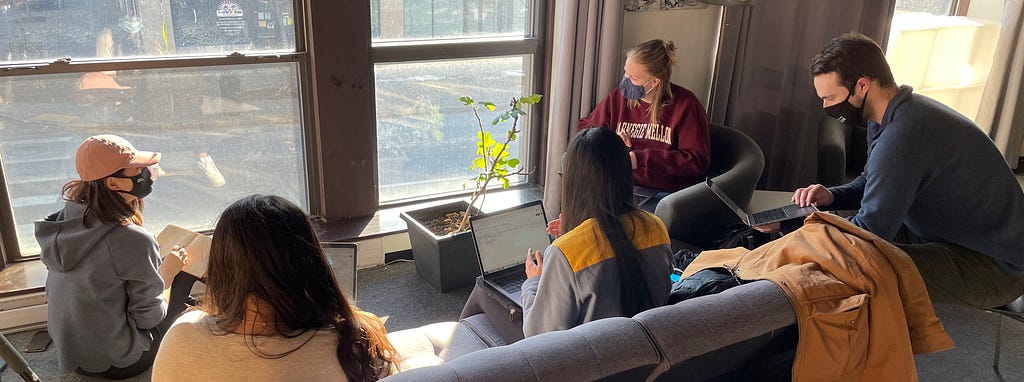 The team members are sitting in an office lounge facing the window, discussing what they’re observing in the intersection outside.