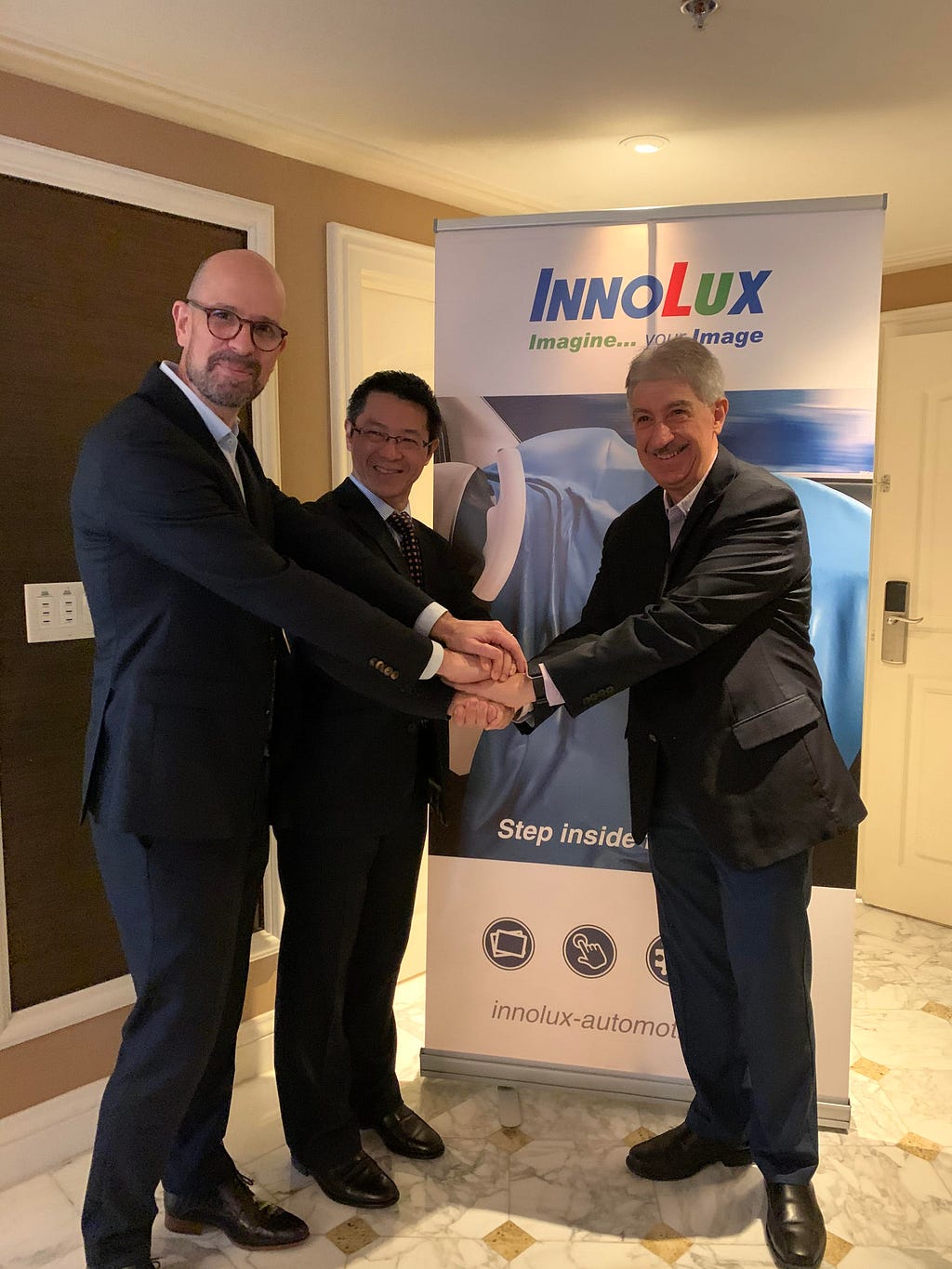 Innolux and Tanvas executives shaking hands in front of an Innolux banner stand