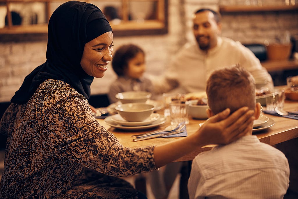 A woman is smiling at the table with her children and partner during evening mealtime.