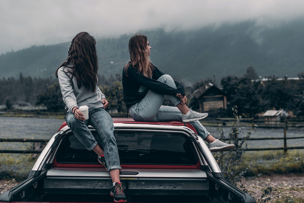 Two girls sitting on a car