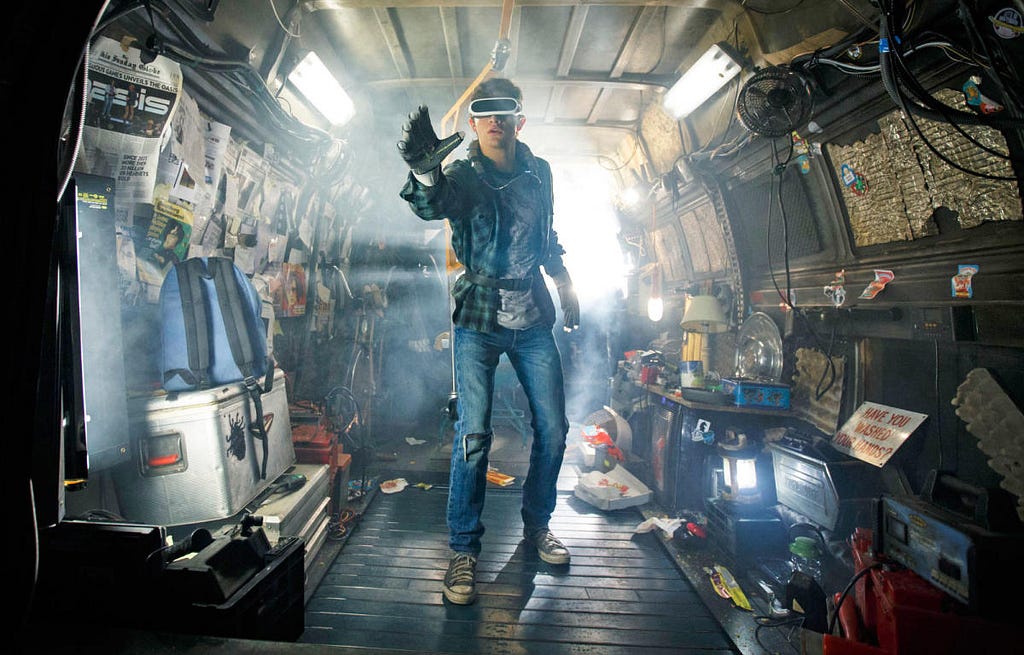 Screen capture from “Ready Player One” move of Wade Watts (Parzival) in his hidden van using his haptic gloves and immersion goggles to play the OASIS alternate reality simulation.