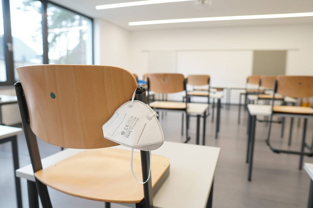 Empty desks with a facemask hanging off one.