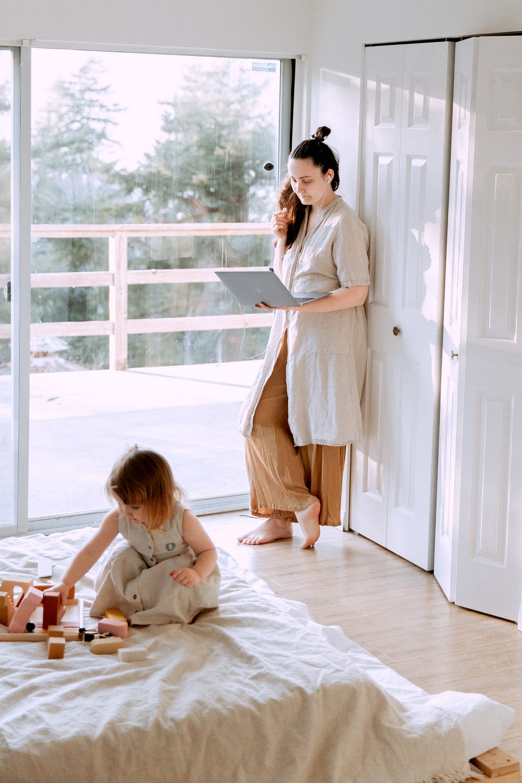 Photo of a woman in a home setting consulting a laptop while a small child plays in the foreground