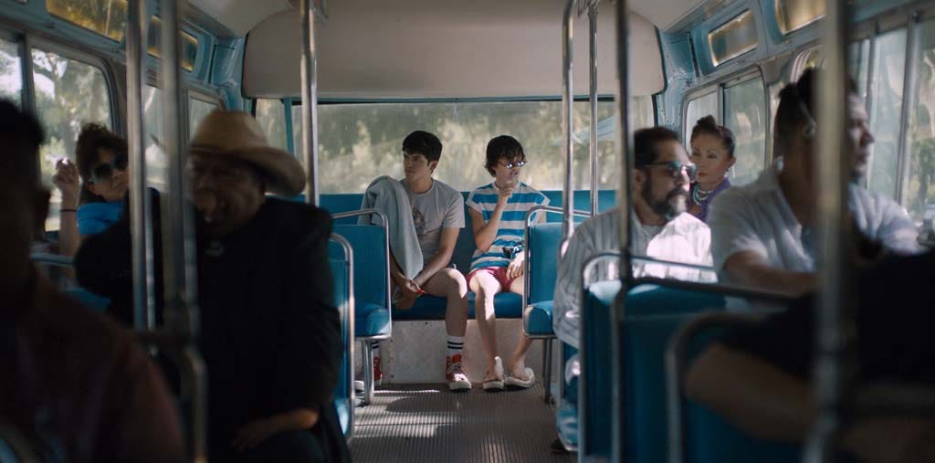 Image of Ari and Dante as they sit on a bus after a day at the pool. The camera is centered on the two.