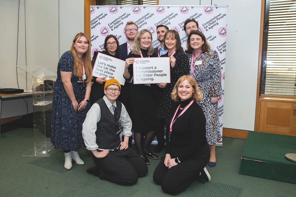 Group of Independent Age employees standing in and holding a sign. Text reads: I support a Commissioner for Older people and Ageing