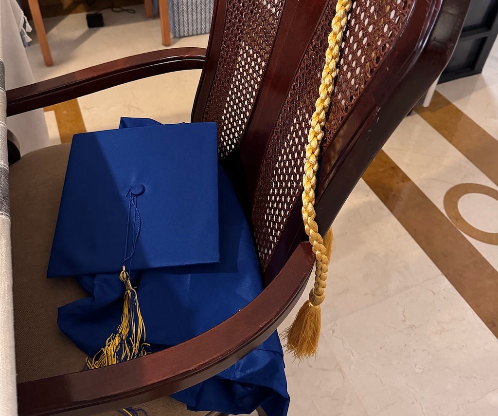 blue cap and gown strewn on chair