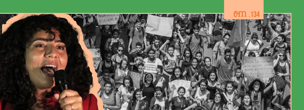 Imagem da candidata Paula Aparecida com um microfone na mão e um protesto de estudantes em 2015 ao fundo