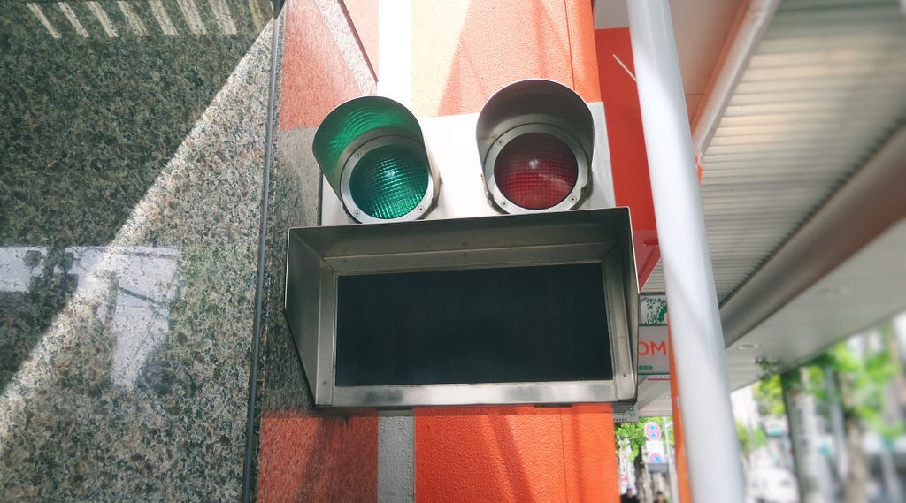 Decorative photo: Green light, red light, and a grate. In the rough shape of a face