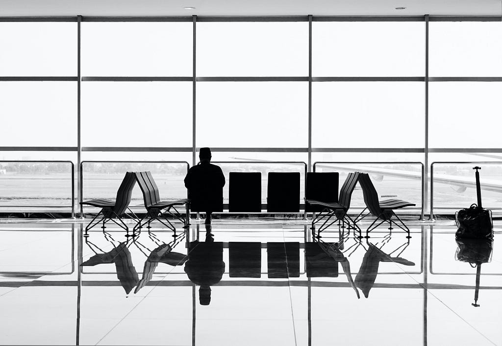 A photo of a man sitting in a gate terminal of an airport