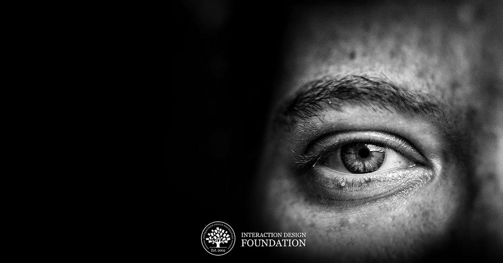 Black and White photograph of a person’s eye, with a small logo of the Interaction Design Foundation at the bottom.