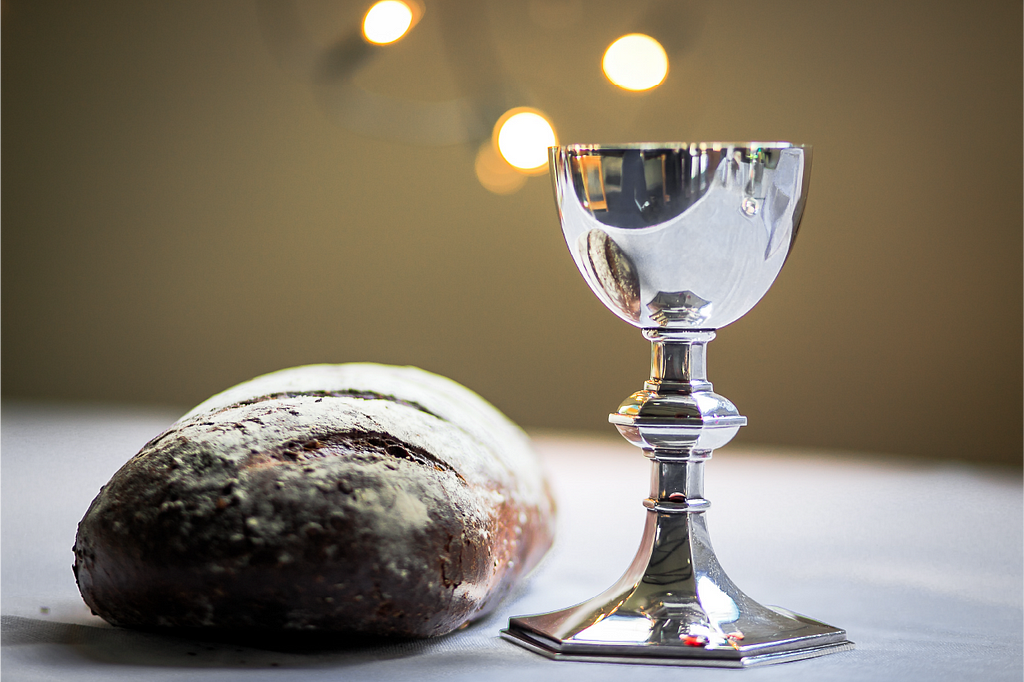 A loaf of bread and a Silver cup of Wine on a Table