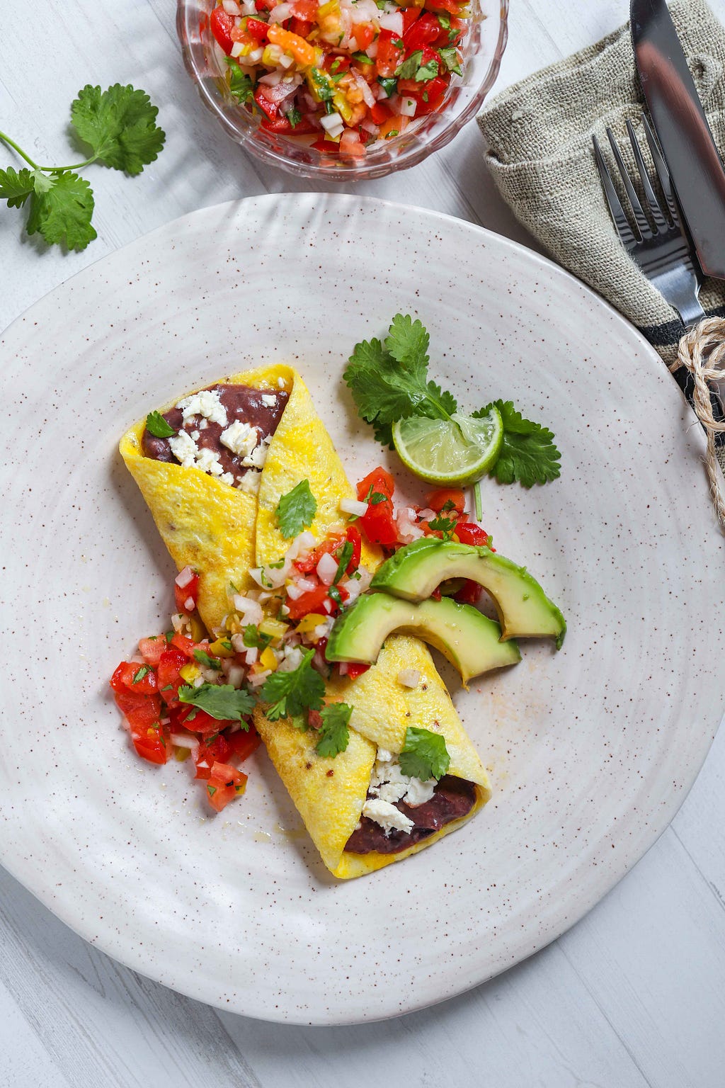black bean omelet garnished with salsa and avocado slices by FIT & NU™.