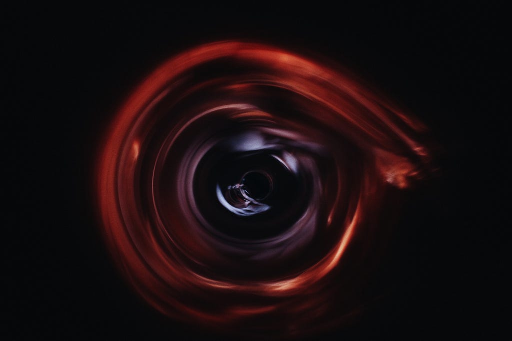 Photo of an orange-tinged vortex with a dark center.