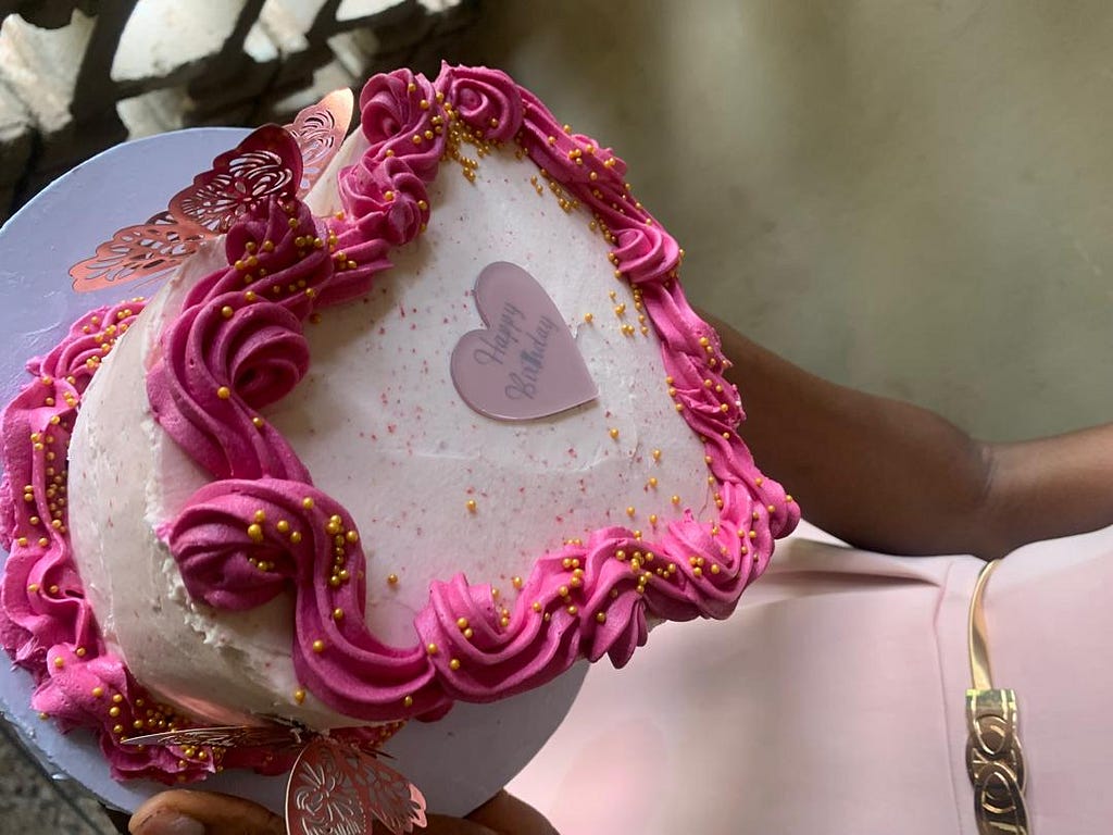 Me in a pink dress with a gold dress, holding a pink cake