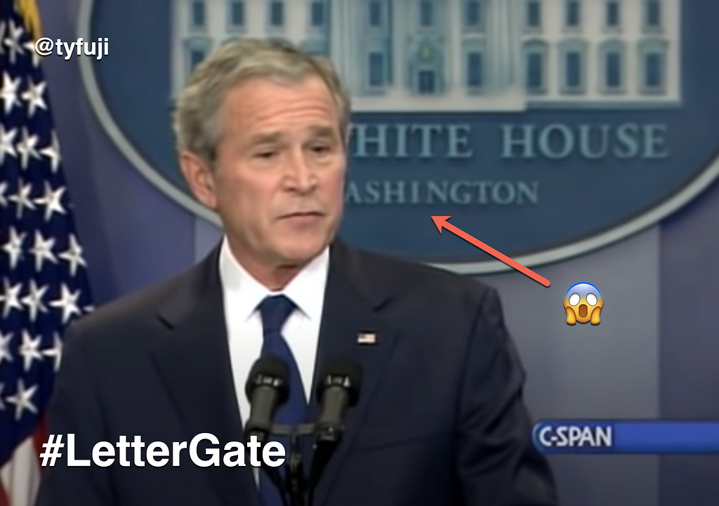 President Bush stands in front of the White House lectern. Behind him is a sign with a design error.